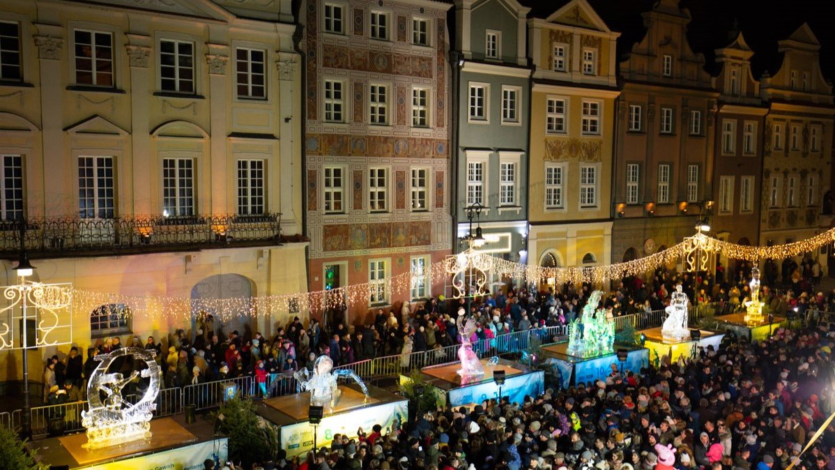 Stary Rynek w Poznaniu, a na nim lodowe rzeźby ustawione na podestach, wokół nich tłum ludzi.