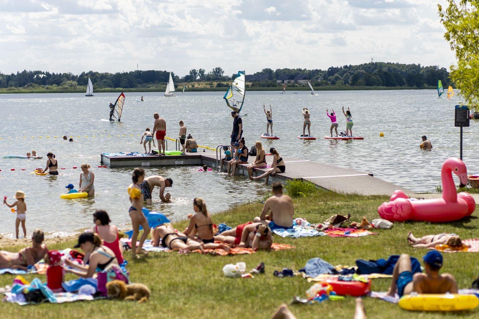 Zdjęcie przedstawia ludzi na plaży i w wodzie. - grafika artykułu