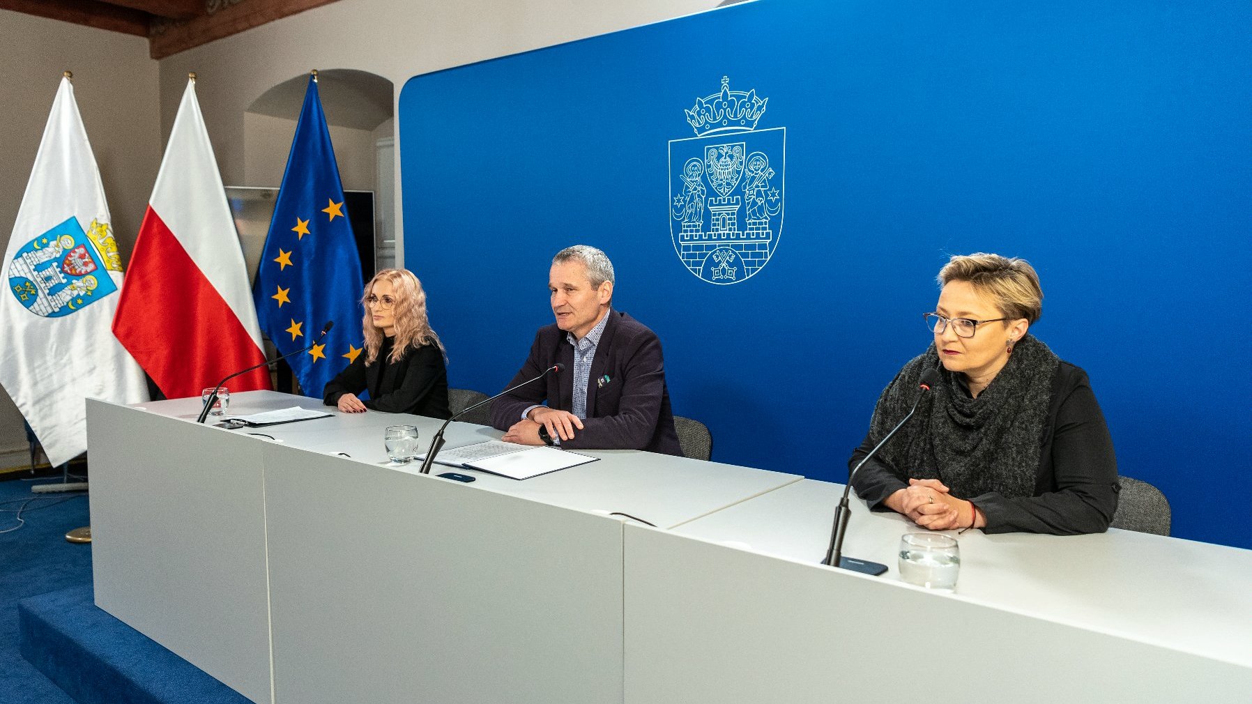 Na zdjęciu trzy osoby za stołem konferencyjnym, w środku Jędrzej Solarski, zastępca prezydenta Poznania