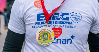 Zdjęcie przedstawia człowieka w koszulce biegu z medalem na szyi.