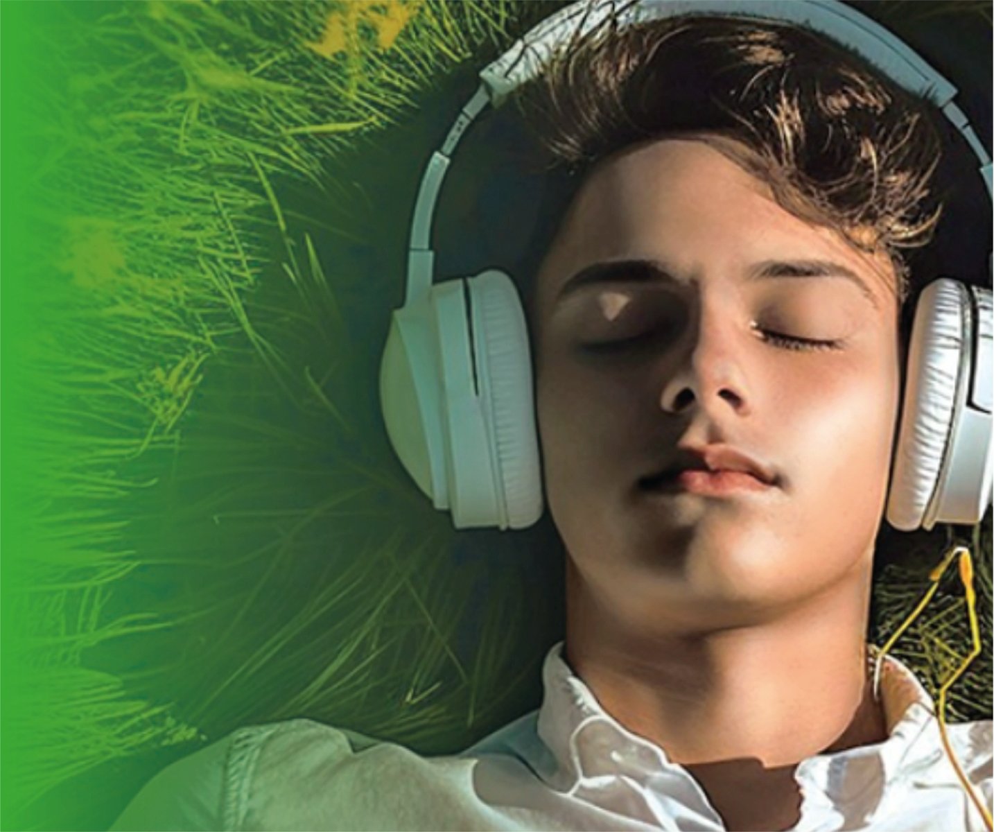 zdjęcie przedstawia twarz nastolatka w słuchawkach, który leży na trawie - grafika artykułu