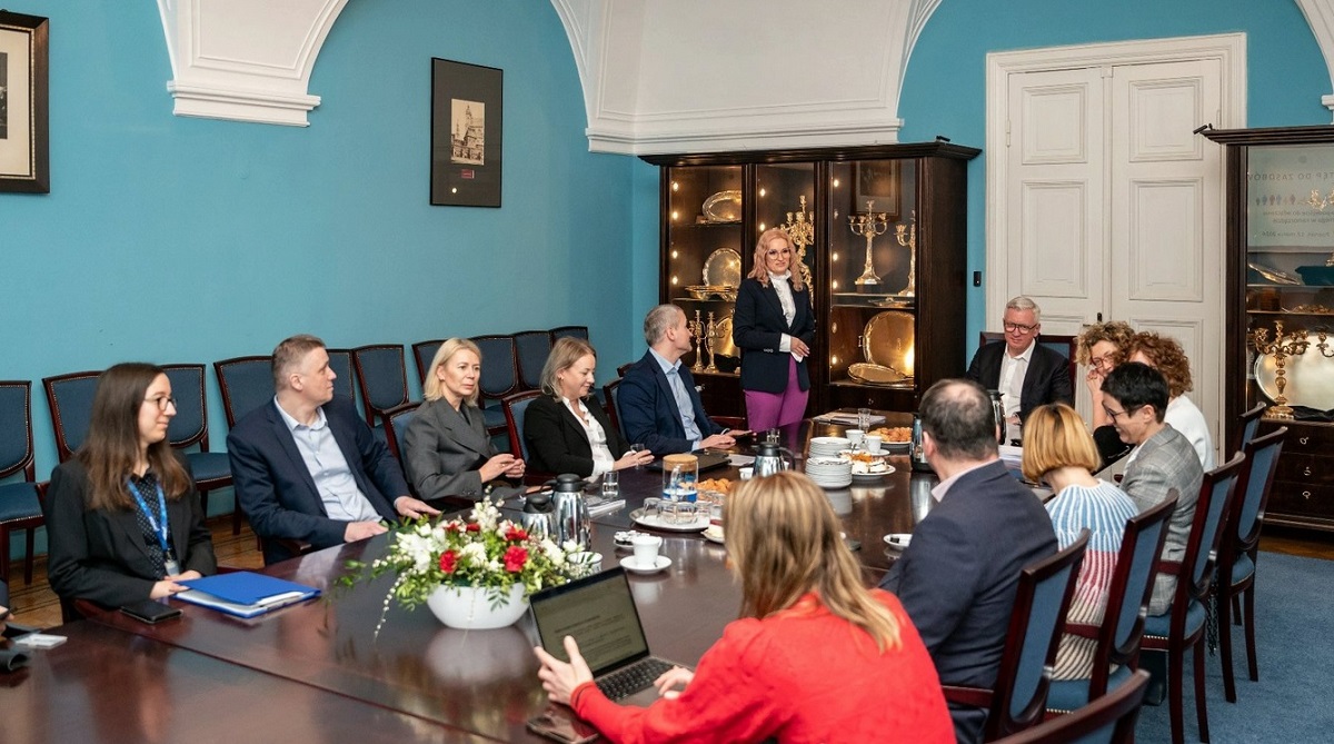 zdjęcie przedstawia ludzi siedzących przy długim stole w błękitnej sali - w trakvie spotkania z prezydentem - grafika artykułu