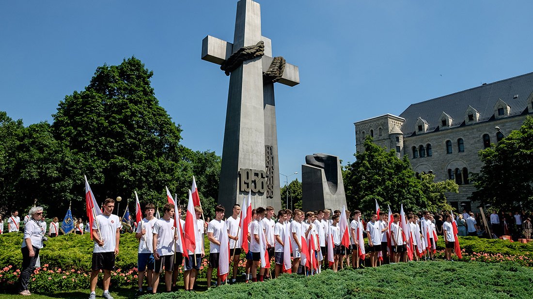 Młodzież z flagami Polski przed pomnikiem