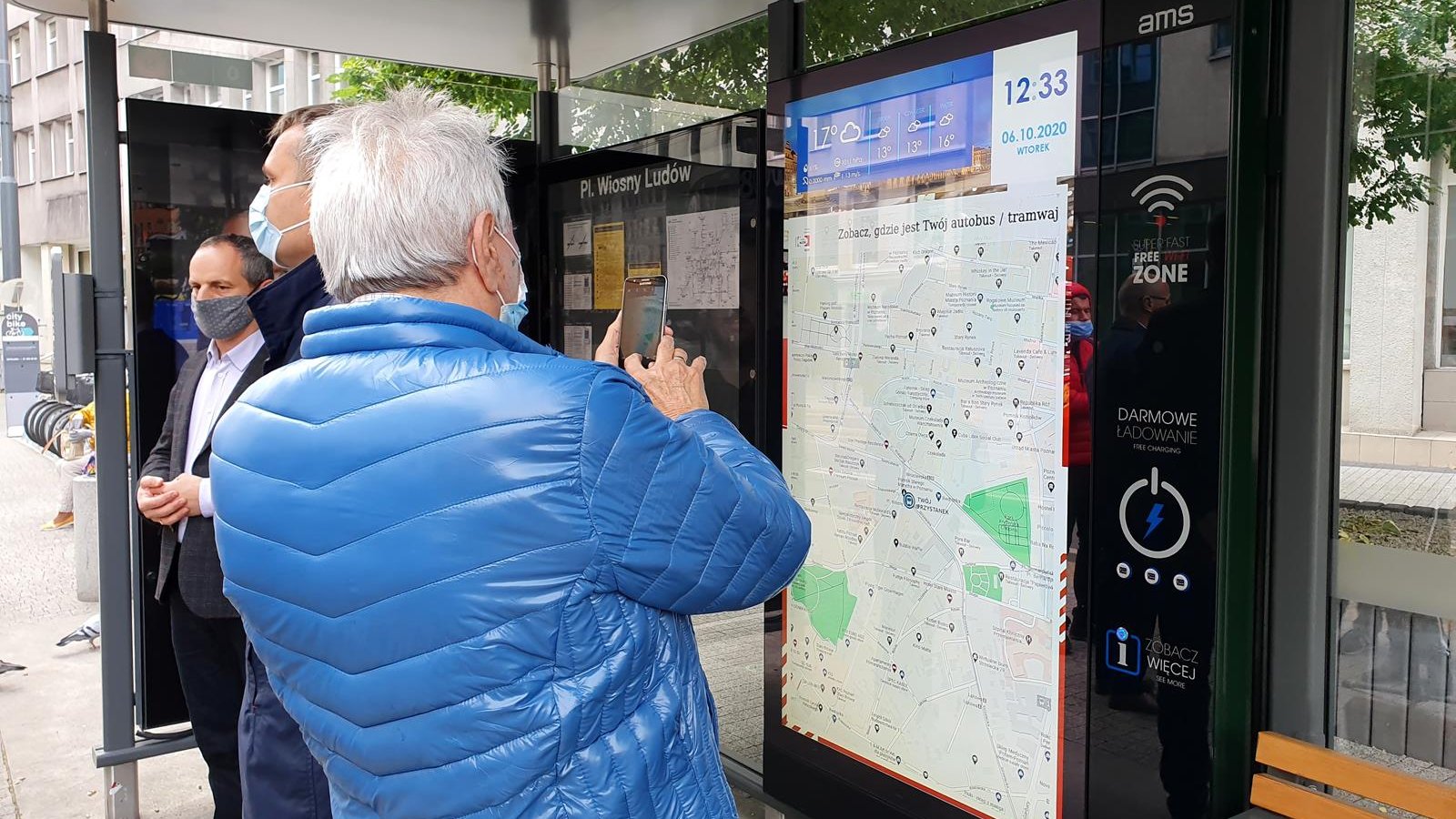 Osoba czekająca na przystanku robi zdjęcie nowego panelu z informacją pasażerską