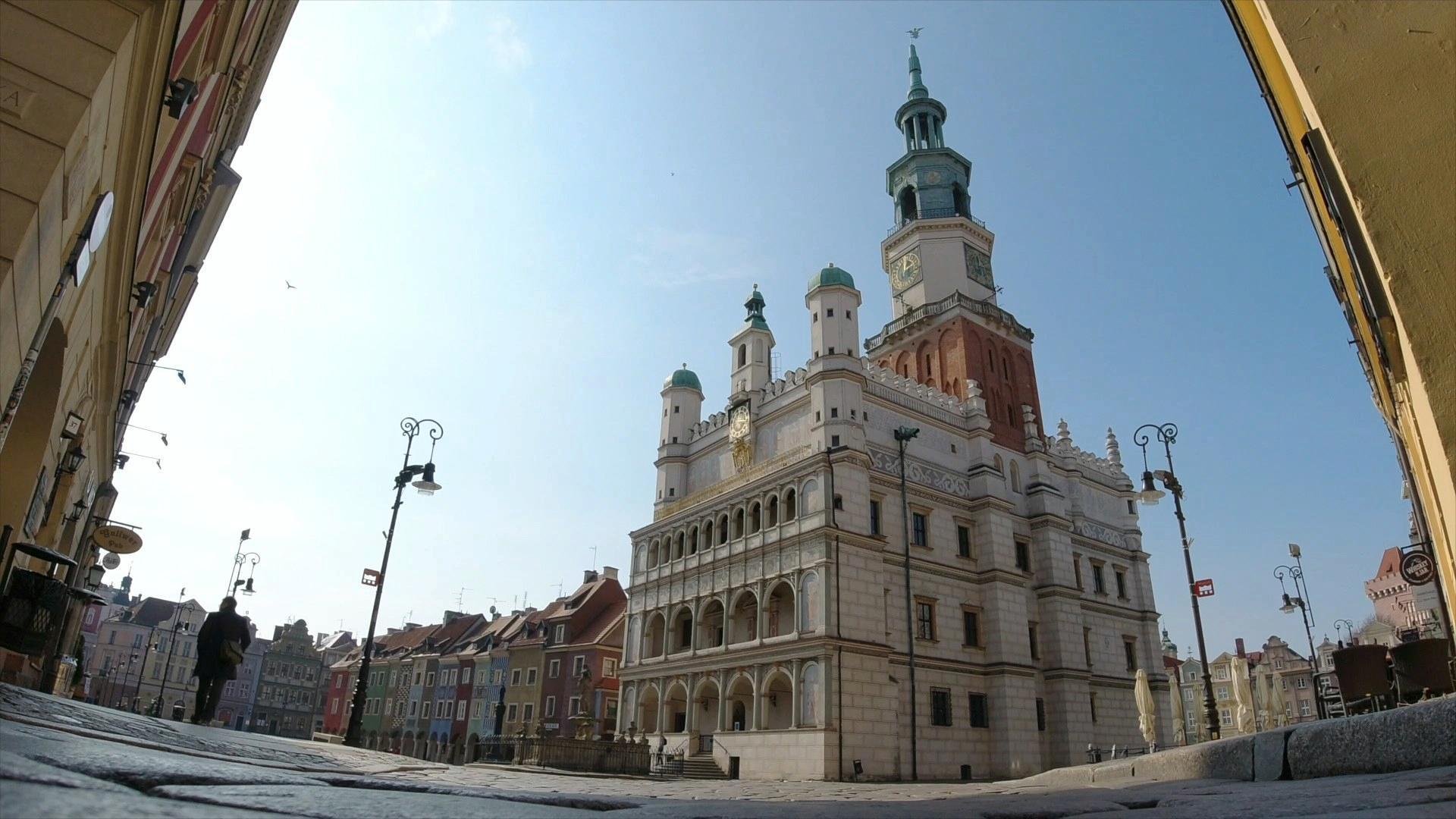 Zdjęcie przedstawia poznański Ratusz na Starym Rynku, widziany spod arkady