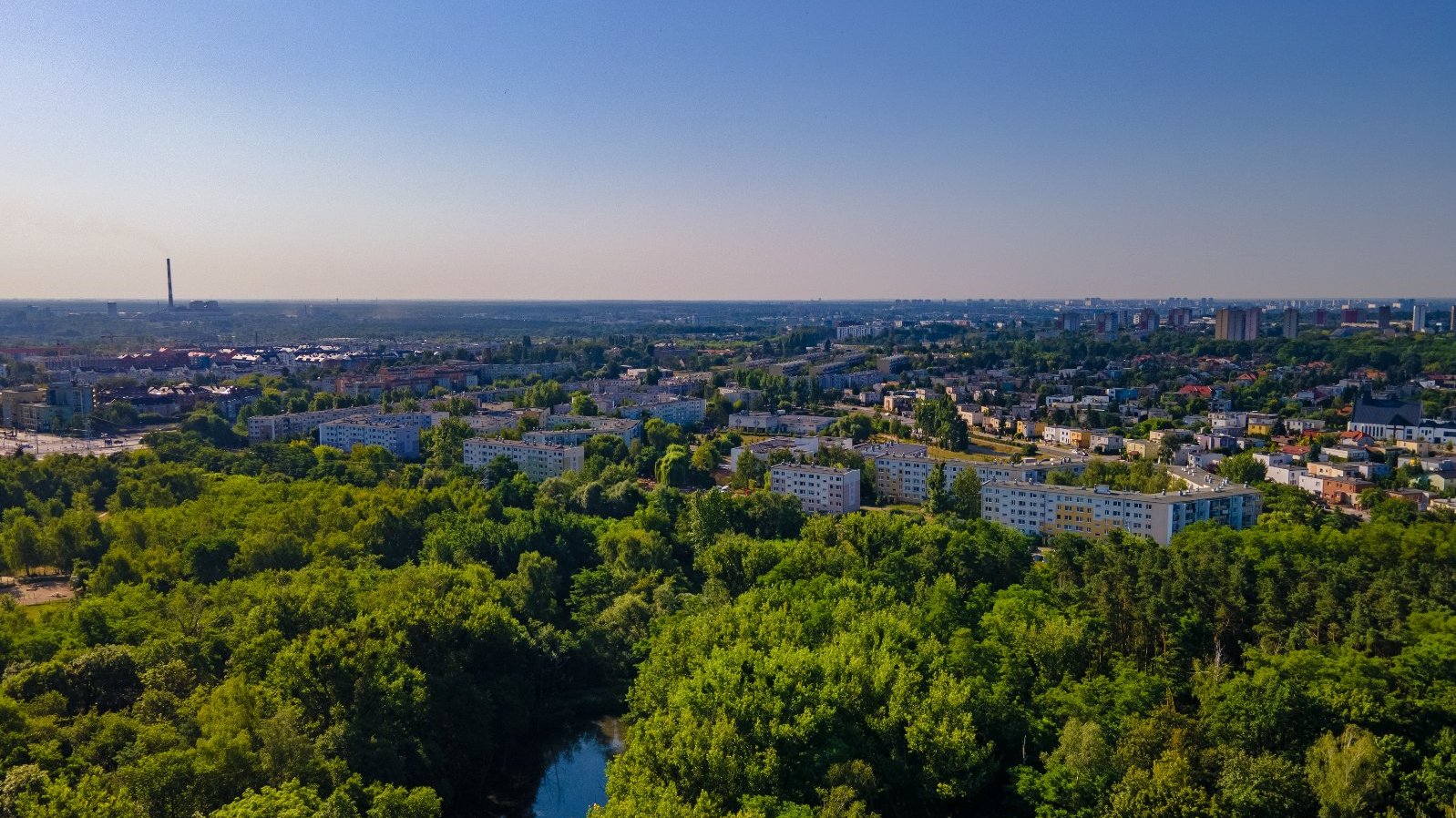 Zdjęcie przedstawia zieleń i budynki z lotu ptaka.