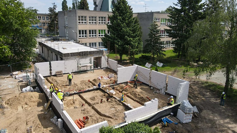 Zdjęcie przedstawia plac budowy z robotnikami z góry.