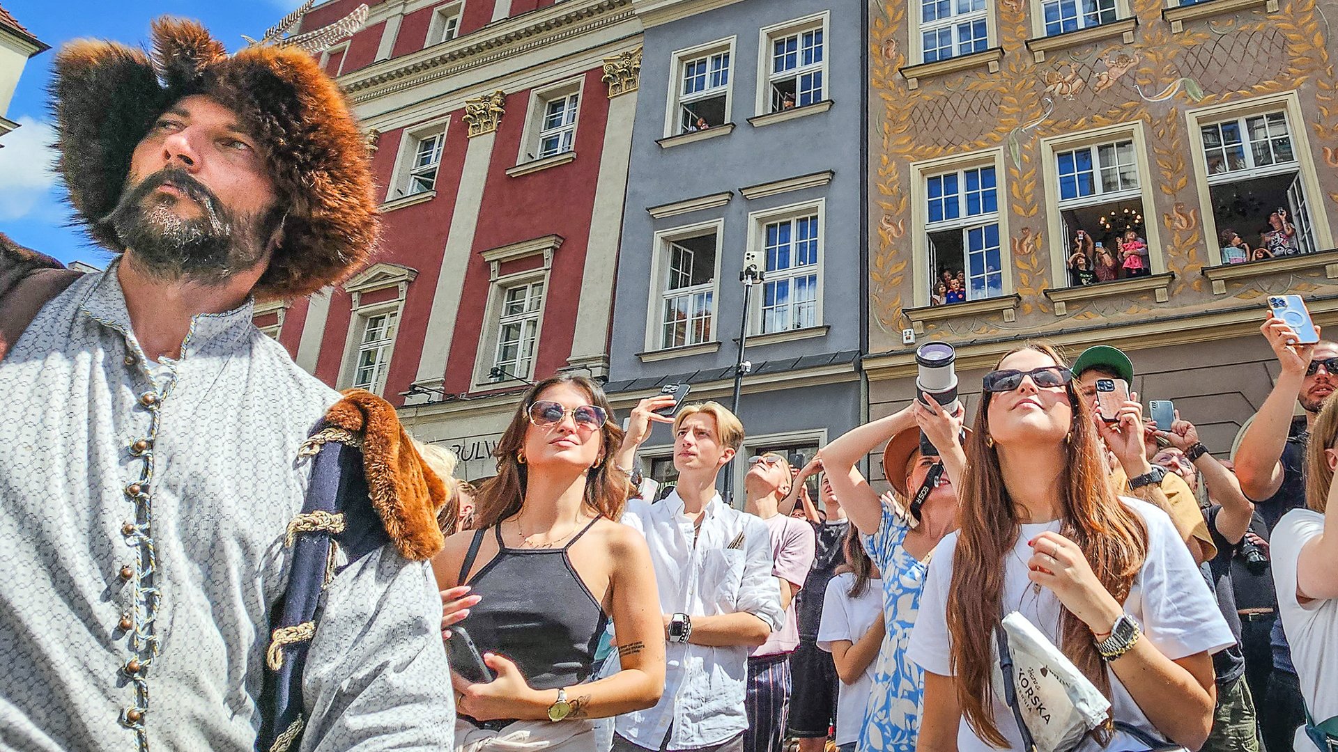 Na zdjęciu grupa młodych ludzi na Starym Rynku, obok mężczyzna w historycznym stroju - grafika artykułu