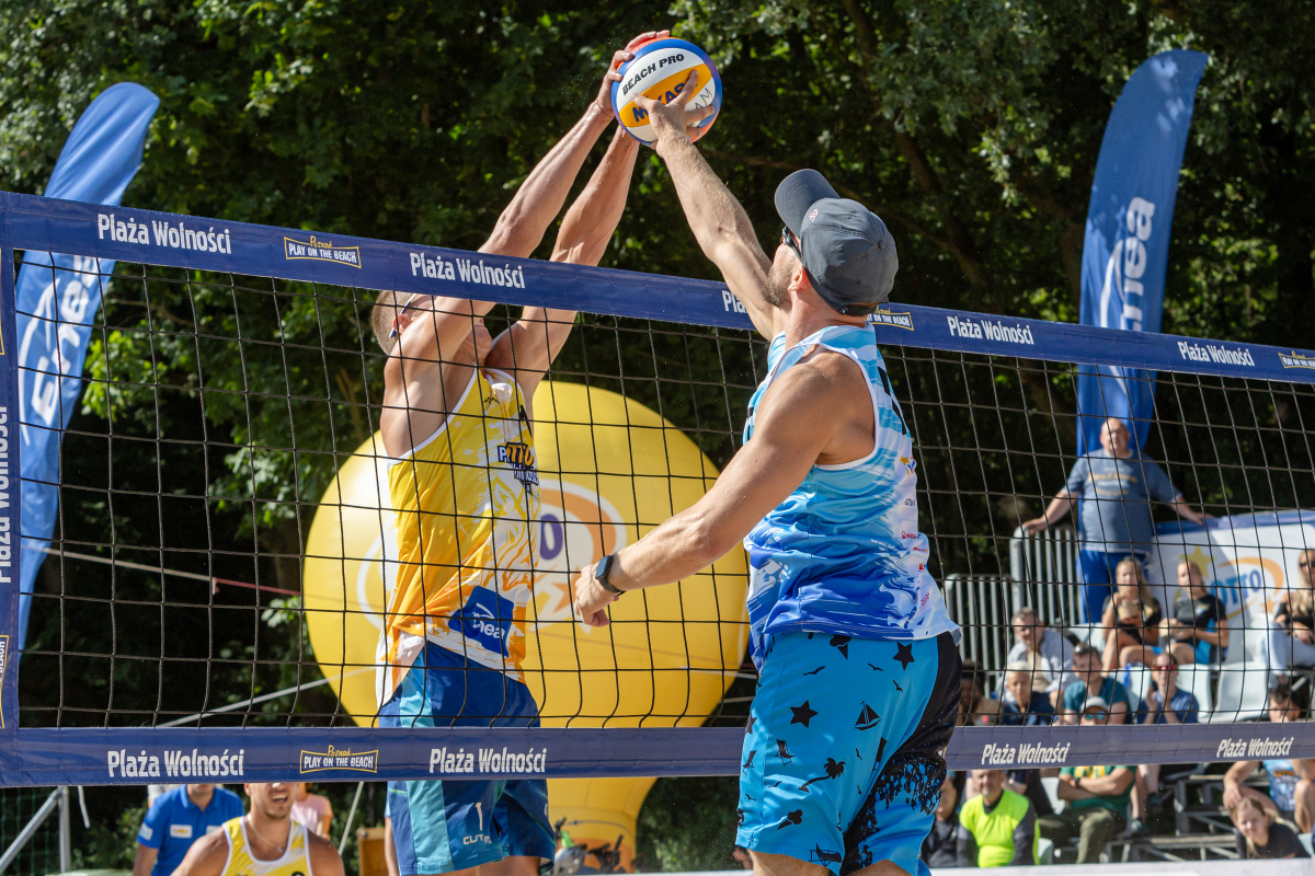 Zdjęcie siatkarzy plażowych wyskakujących do piłki nad siatką - grafika artykułu