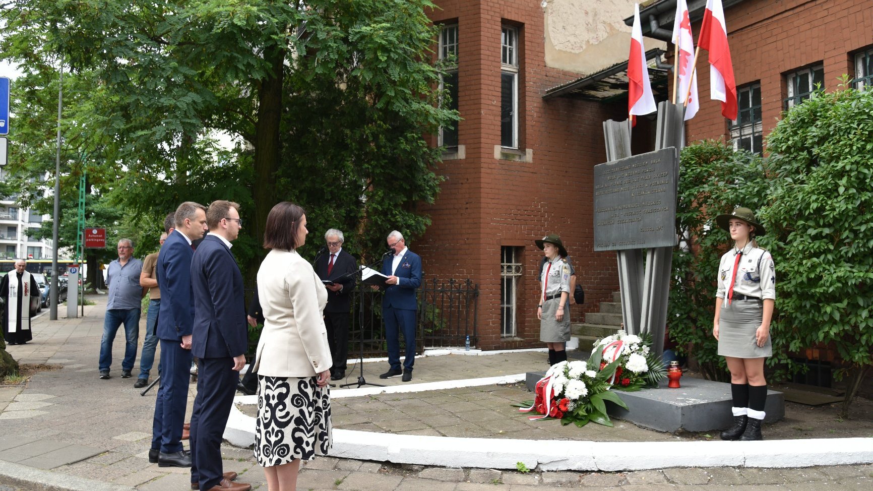 Na zdjęciu delegacja składająca kwiaty pod tablicą