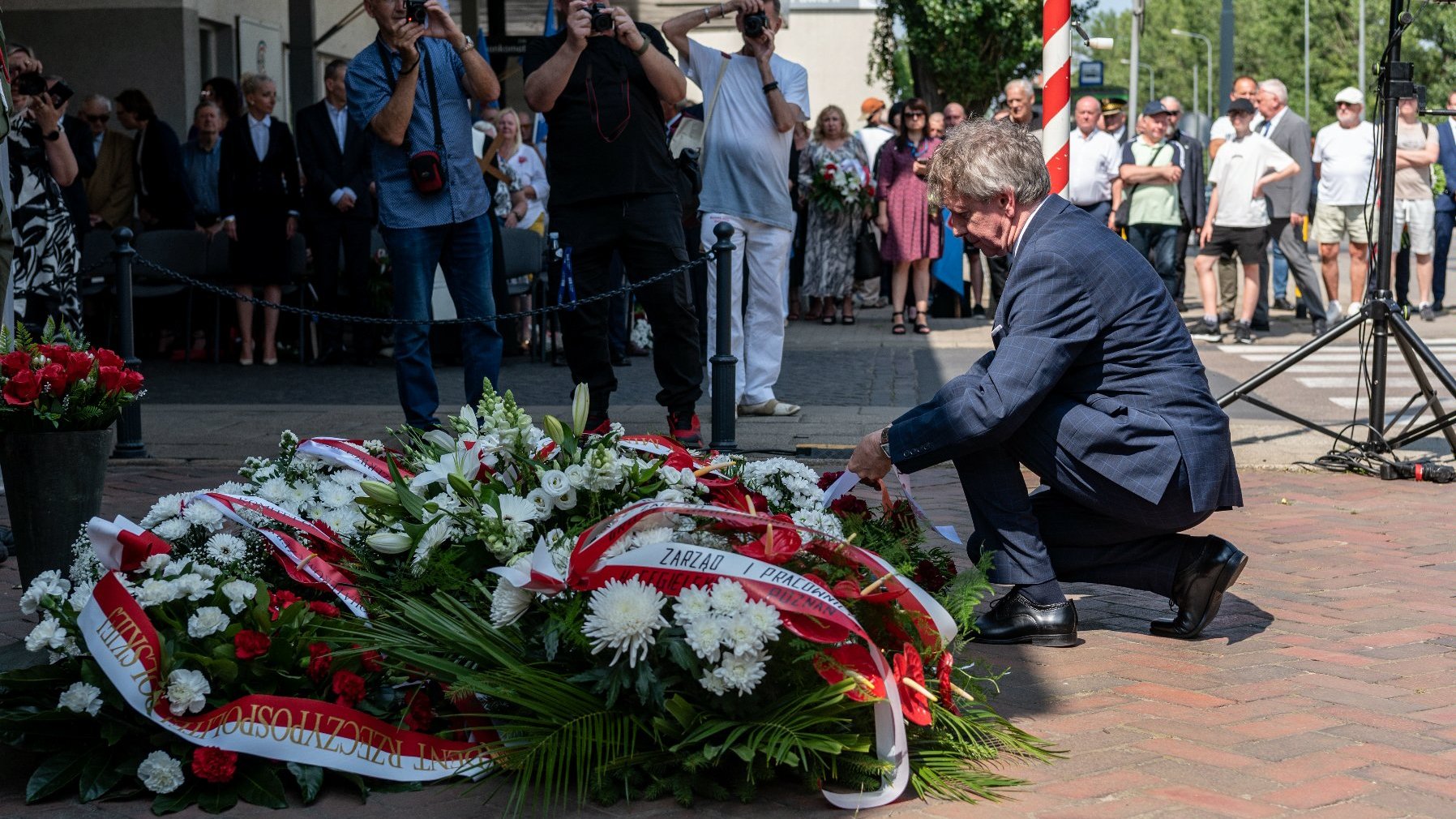 Na zdjęciu mężczyzna składający wiązankę kwiatów