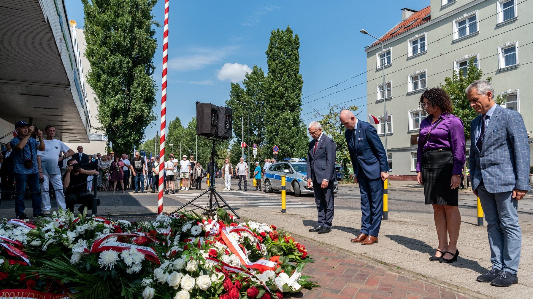 Na zdjęciu delegacja składająca kwiaty przed tablicą