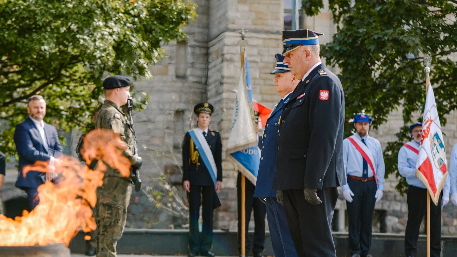 Zdjęcie przedstawia mężczyzn z mundurach składających kwiaty.