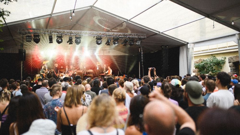 Koncert na jasno oświetlonej scenie, tłum stoi pod sceną.