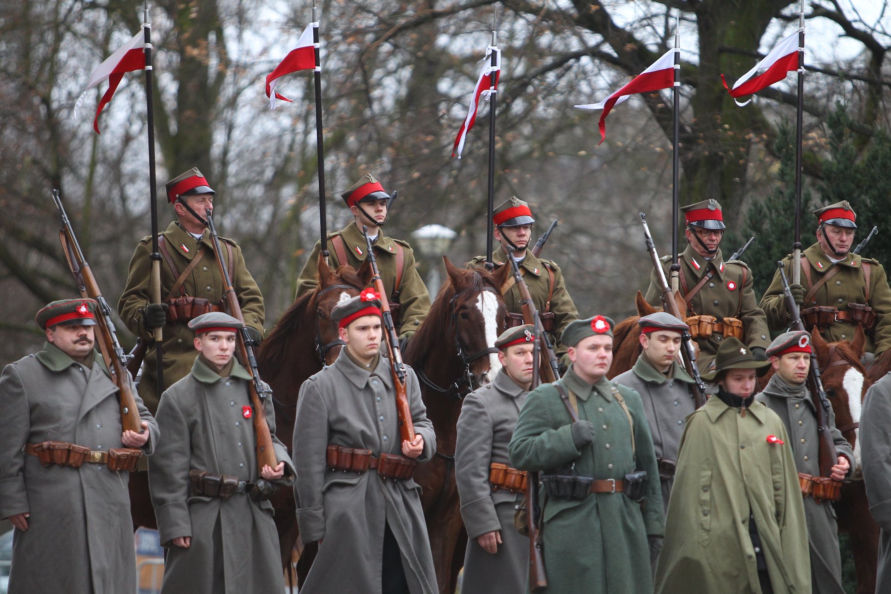 Dwa rzędy umundurowanych powstańców (grupa rekonstrukcyjna), podczas obchodów powstania wielopolskiego. Z przodu stoją zbronią na ramieniu, z tłu są na koniach. - grafika artykułu