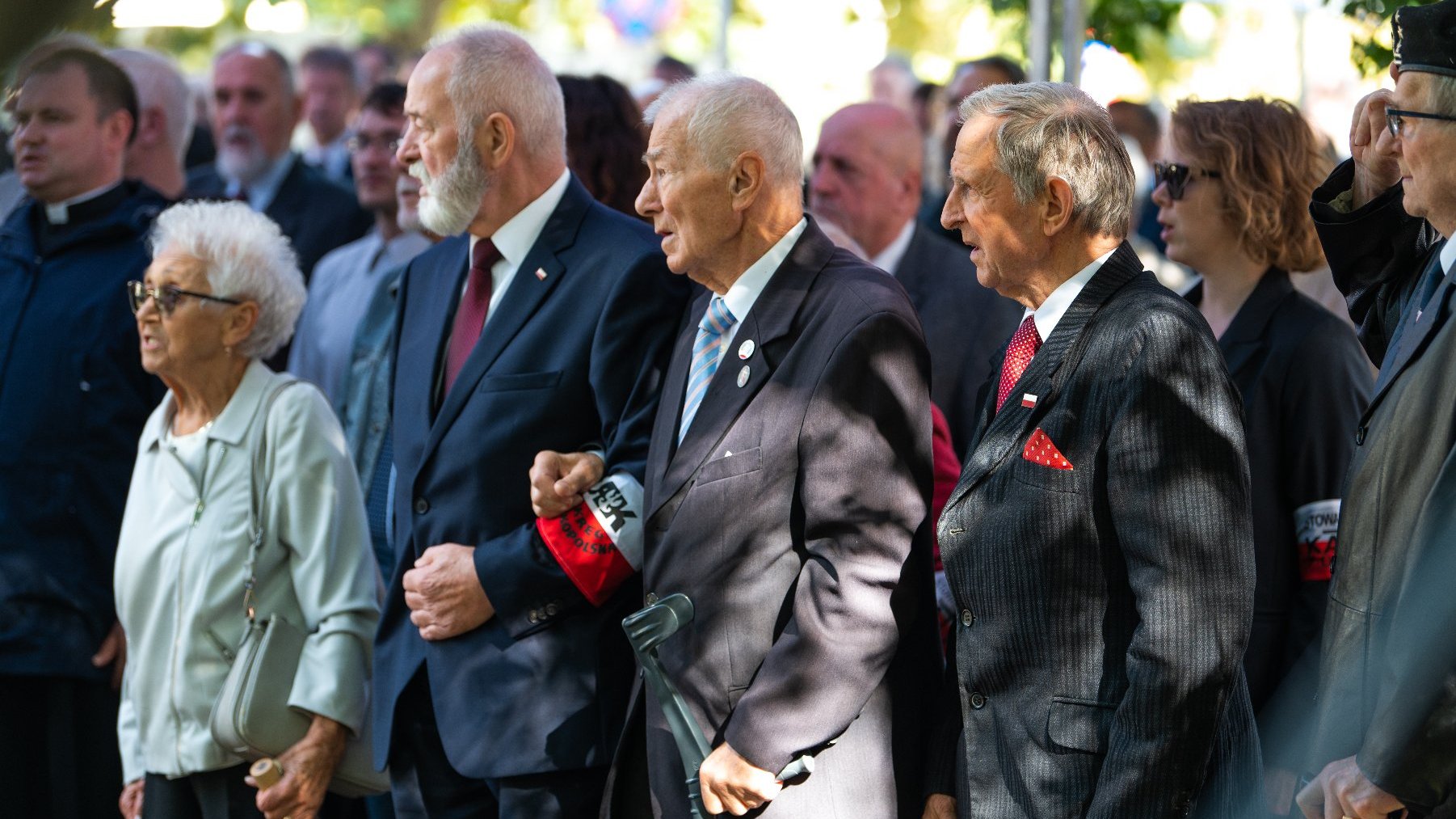 Zdjęcie przedstawia stojących ludzi.