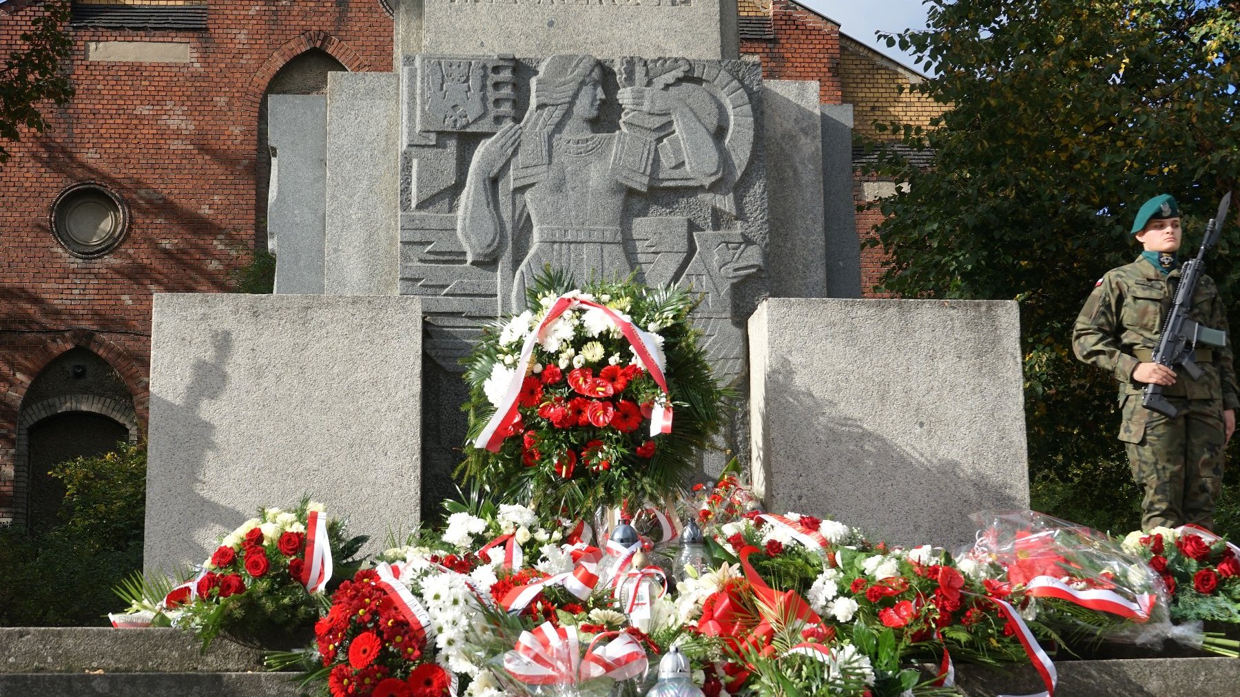 Na zdjęciu pomnik, pod nim wiązanki