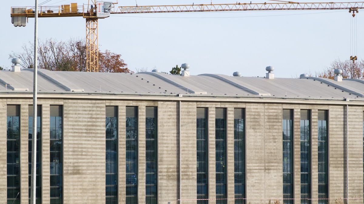 Zdjęcie przedstawia duży budynek i żurawia budowlanego.