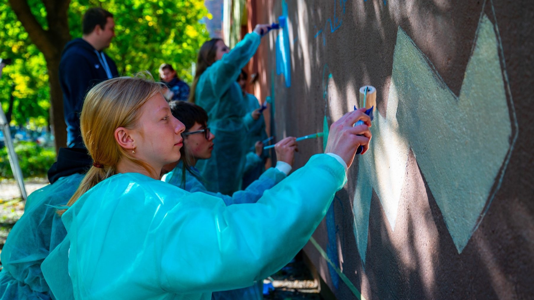 Zdjęcie przedstawia ludzi malujących mural.