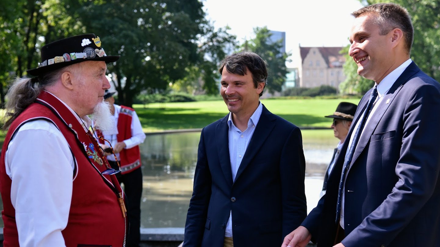 Na zdjeciu trzech mężczyzn, w tym prezydent Poznania i członek zespołu, rozmawiają