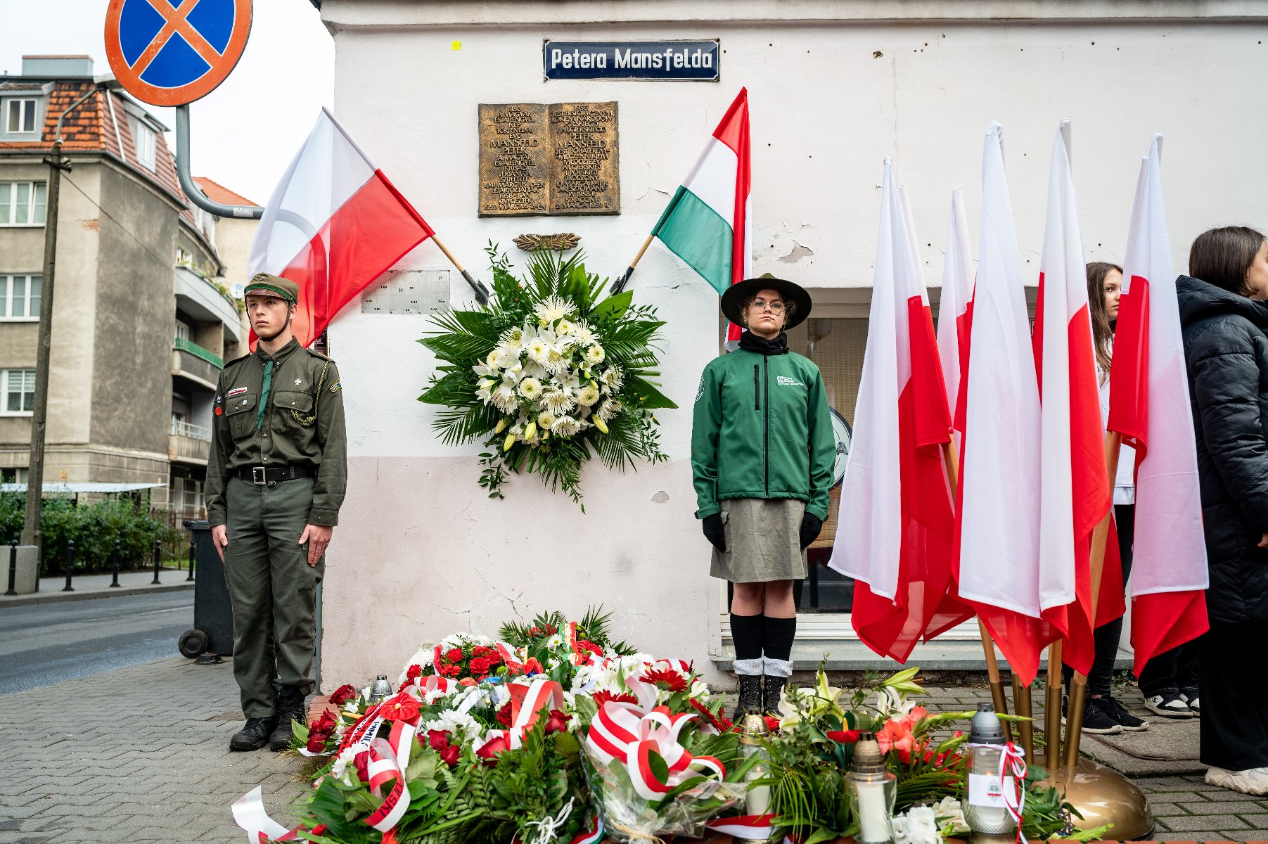 Galeria zdjęć przedstawia obchody rocznicy wybuchu Powstania Węgierskiego, podczas których złożono kwiaty pod tablicami upamiętniającymi Pétera Mansfelda i Romka Strzałkowskiego. - grafika artykułu