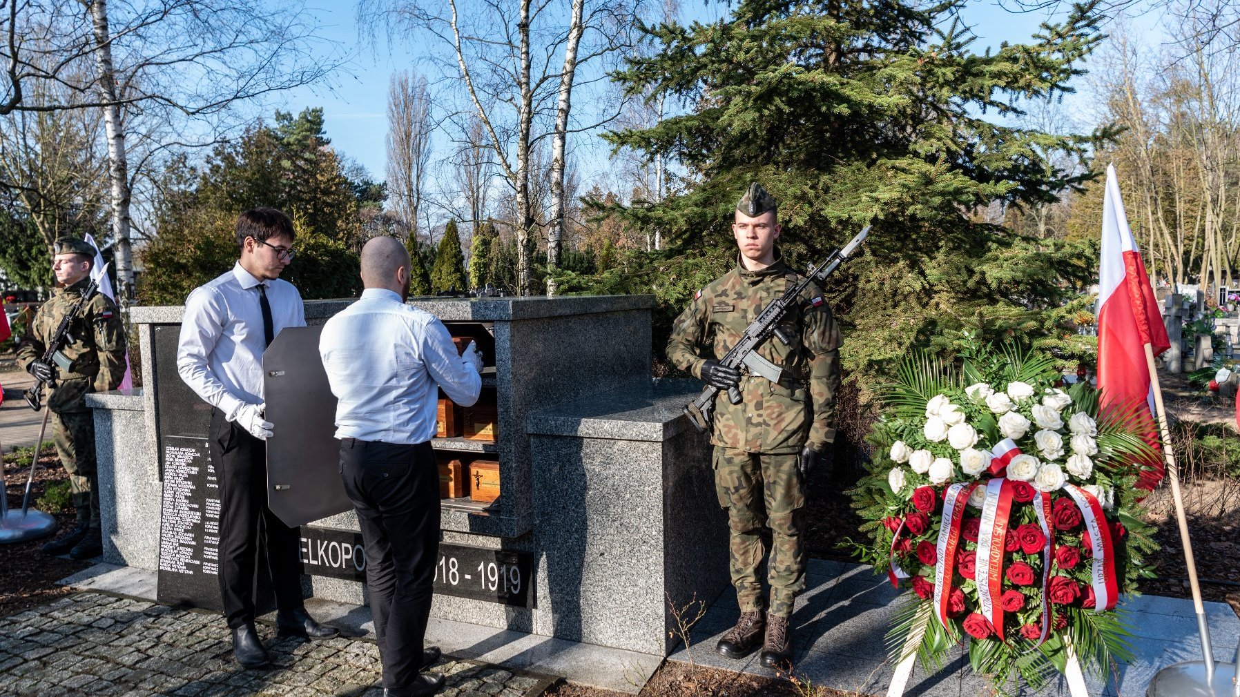 na zdjęciu pracownicy cmentarza wkładają urny do kolumbarium