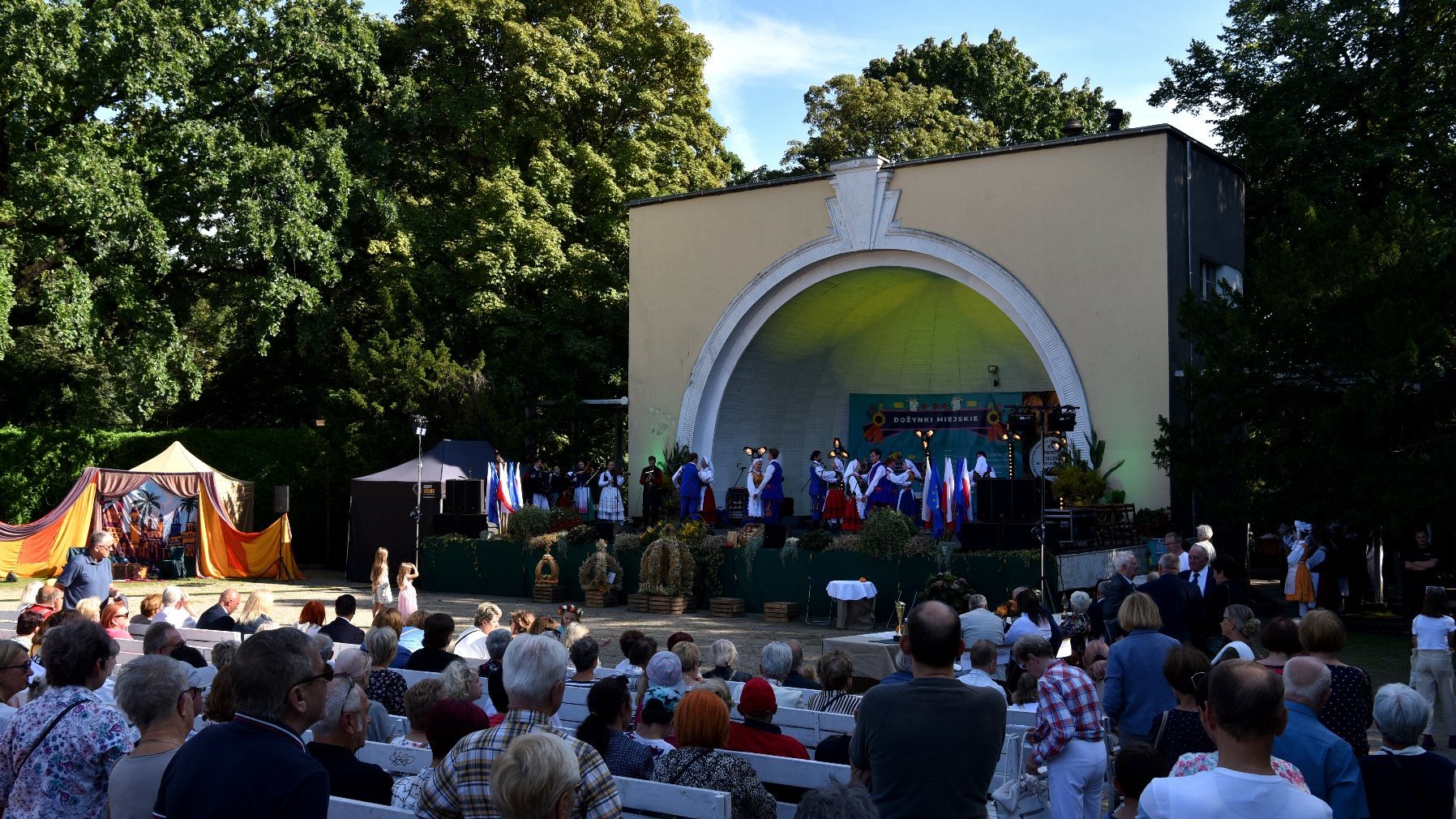 Zdjęcie przedstawia scenę na której tańczą ludzie oraz oglądajacych pokaz widzów.