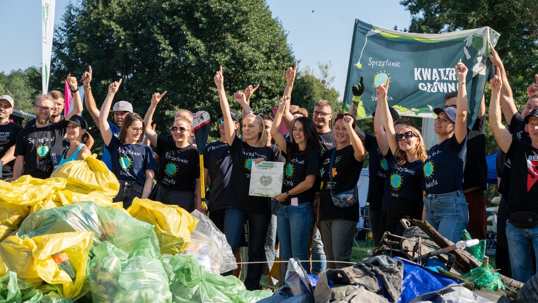 Zdjęcie przedstawia grupę ludzi i zebrane przez nich śmieci.