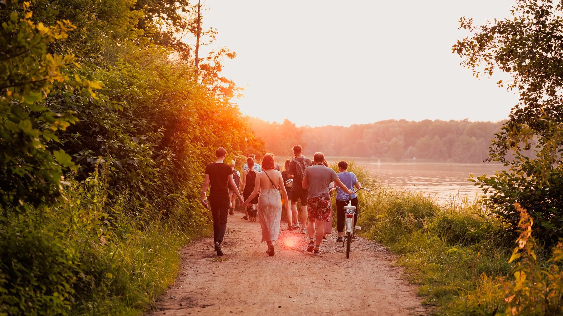 Na zdjęciu ludzie idący ścieżką nad jeziorem