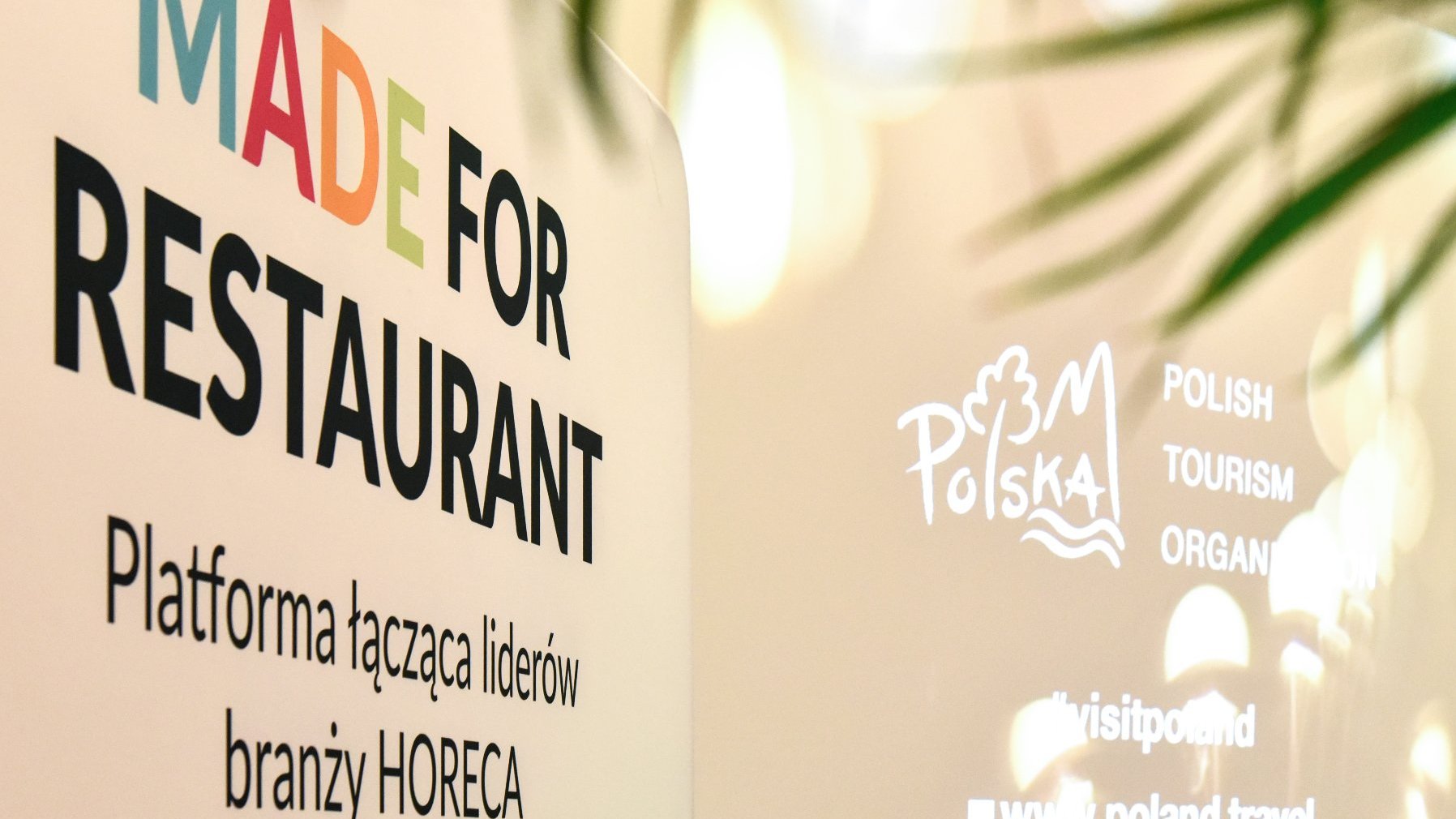 Zdjęcie przedstawia plakat konferencji "Made for Restaurant". Znajdują się na niej kolorowe literki, które stanowią słowo "made". W tle widoczny jest ekran projektora