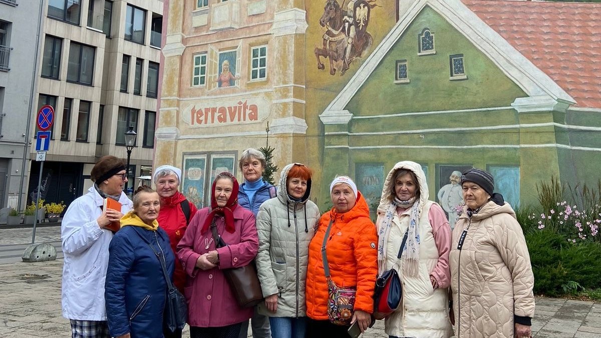 Na zdjęciu seniorki stojące przed muralem na Śródce