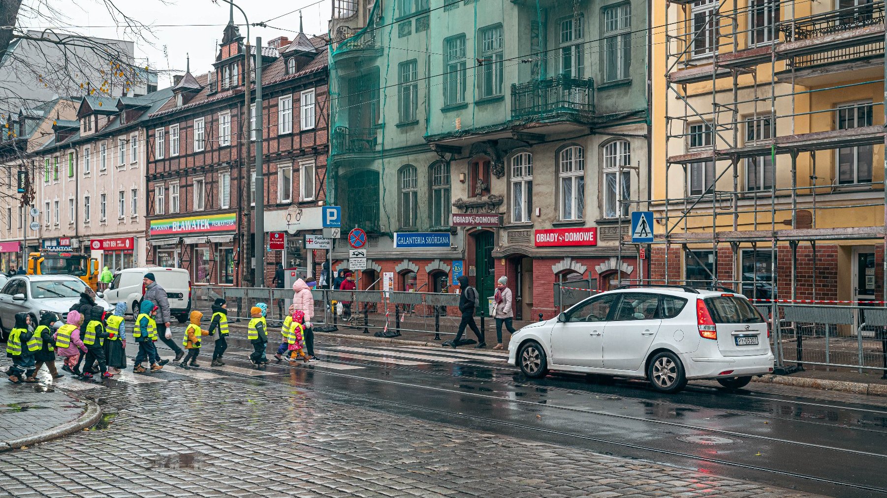 Aktualne przejście dla pieszych na ul. Dąbrowkiego przy ul. Kochanowskiego. Na zdjęciu widac grupę przedszkolaktów przechodzących po pasach i samochód czekający przed