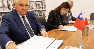 Na zdjęciu trzy osoby za stołem, podpisują porozumienie