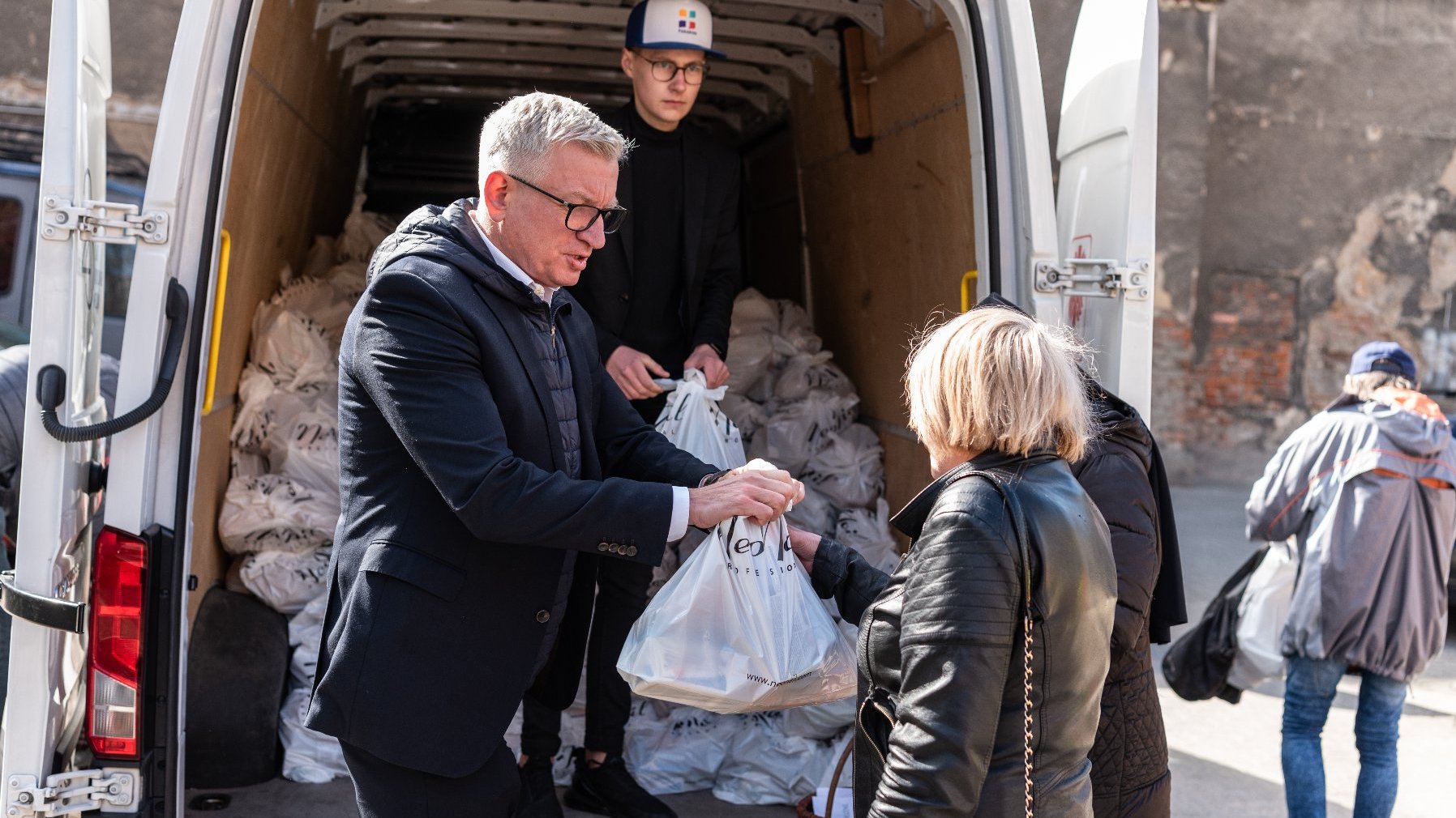 Na zdjęciu prezydent poznania wydający paczki z żywnością ubogim