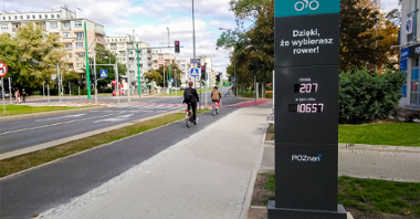 Licznik rowerowy przy ul. Grunwaldzkiej, na drodze rowerowej 2 rowery, po obu stronach bloki.