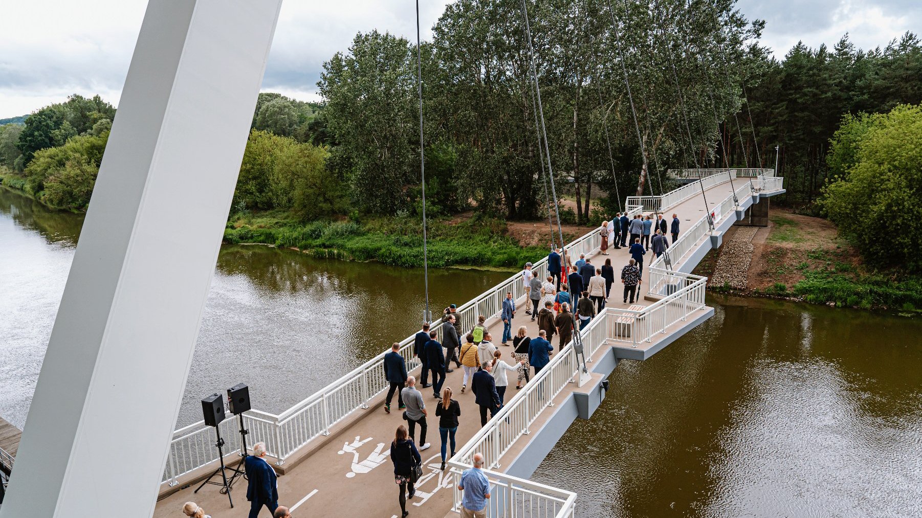 Kładka nad Wartą. Po kładce idą ludzie. W tle drzewa.