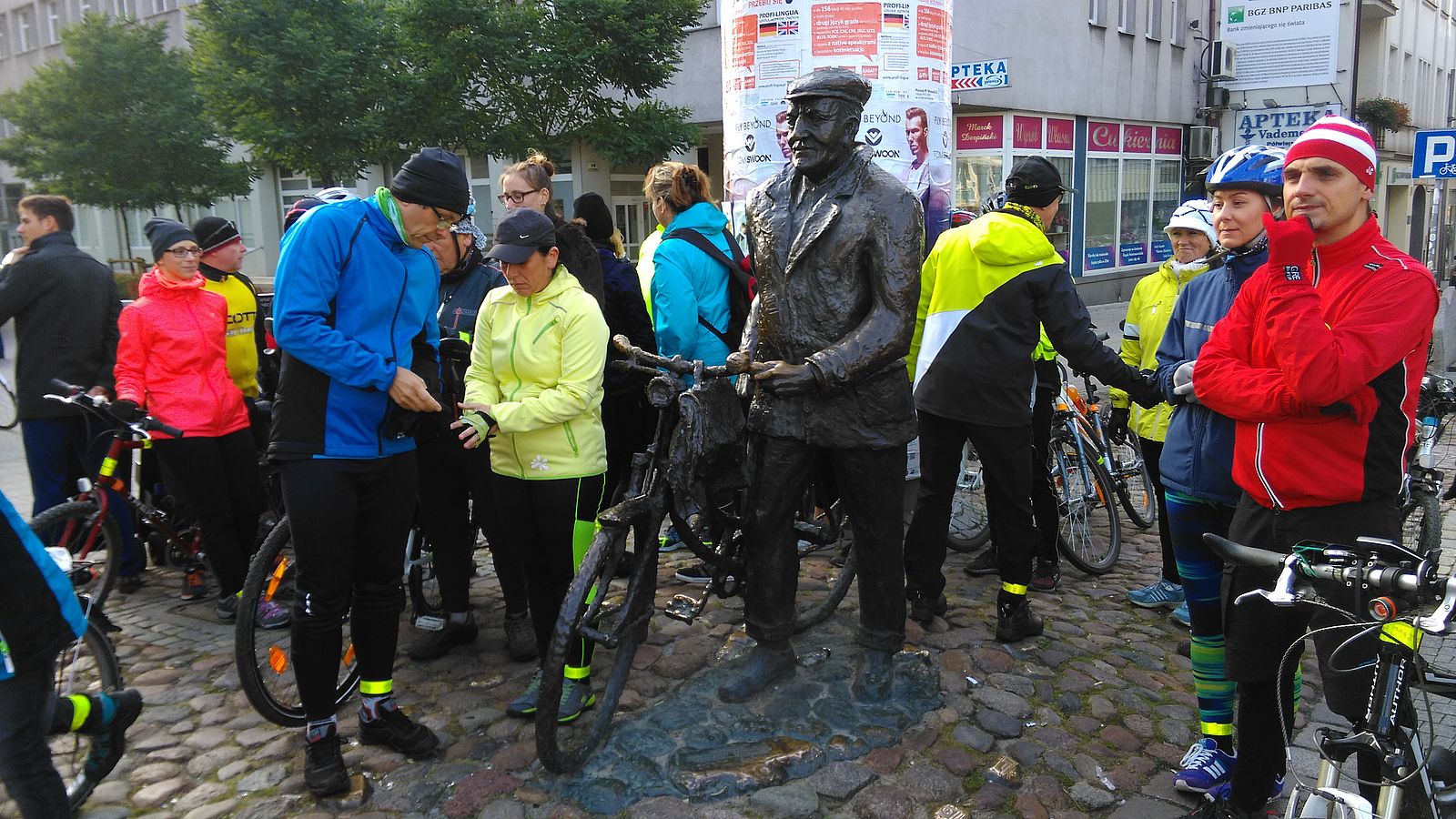 Zdjęcie, grupa rowerzystów przygotowuje się do startu w rajdzie. Są kolorowo ubrani, na głowach mają czapki i kaski rowerowe. - grafika artykułu