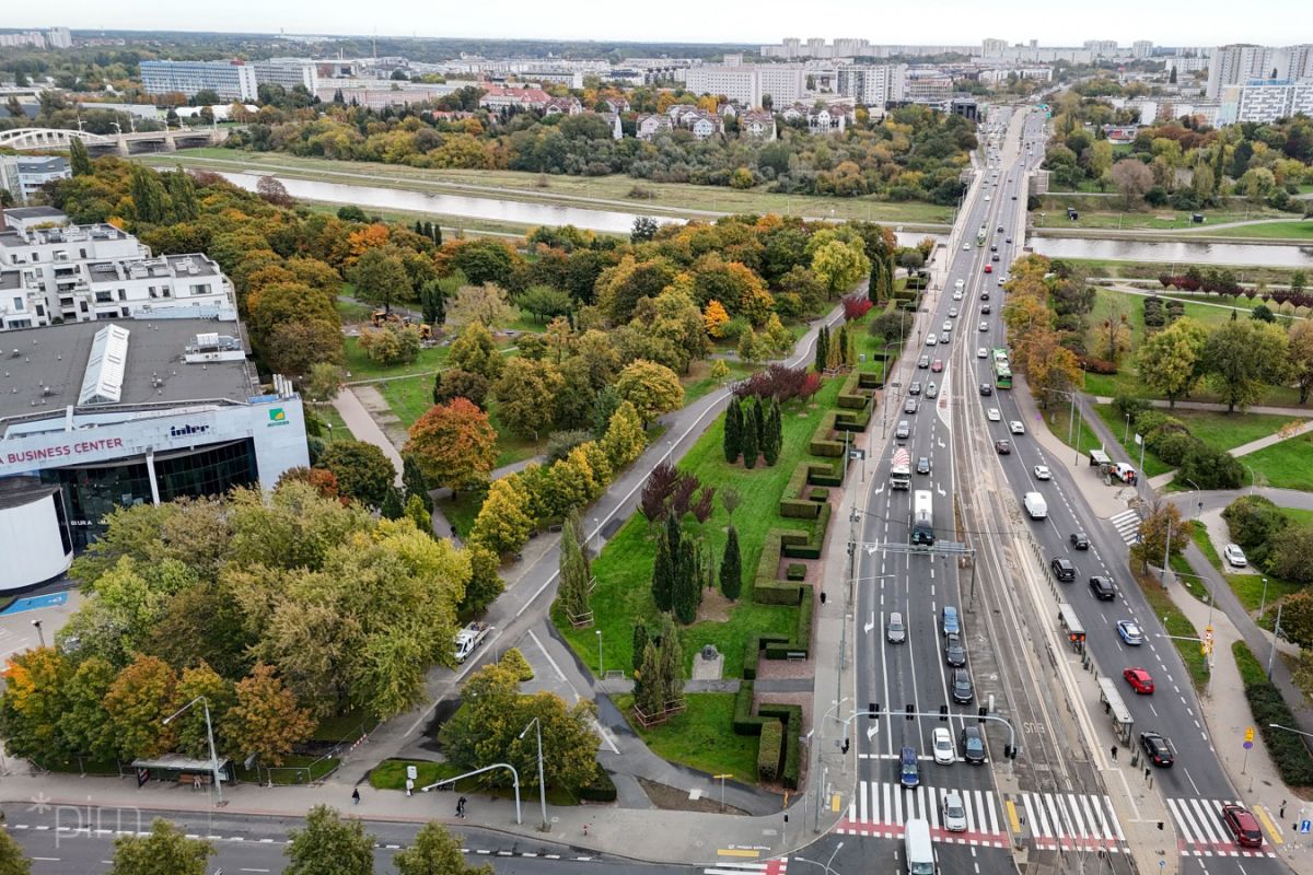 Zdjęcie z lotu ptaka, skrzyżowanie ulic, z przejściami dla pieszych, nowo budowaną drogą rowerową, drzewami rosnącymi wokół. - grafika artykułu