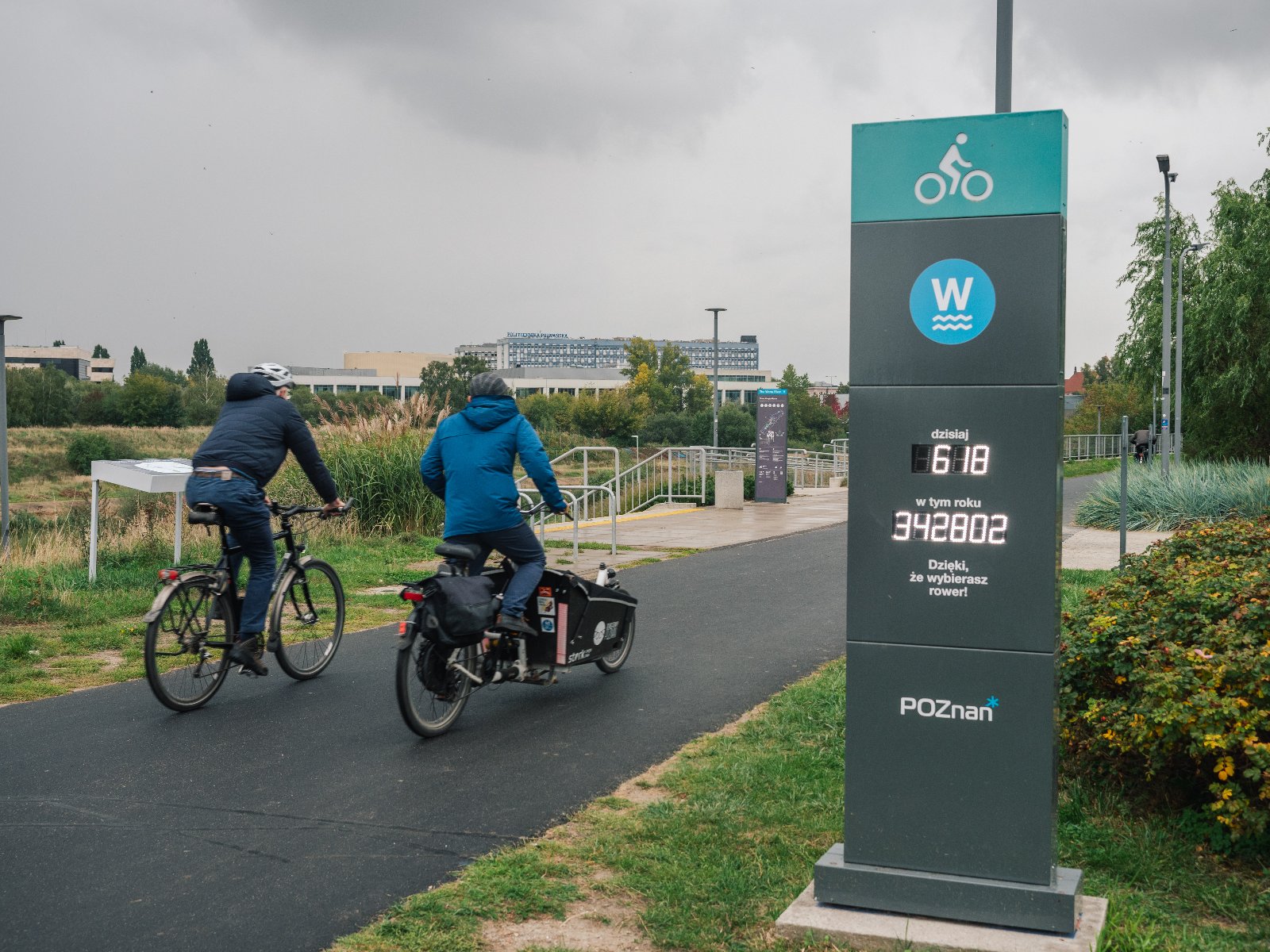 Zdjęcie, dwoje rowerzystów na trasie rowerowej, obok licznik rowerowy. - grafika artykułu