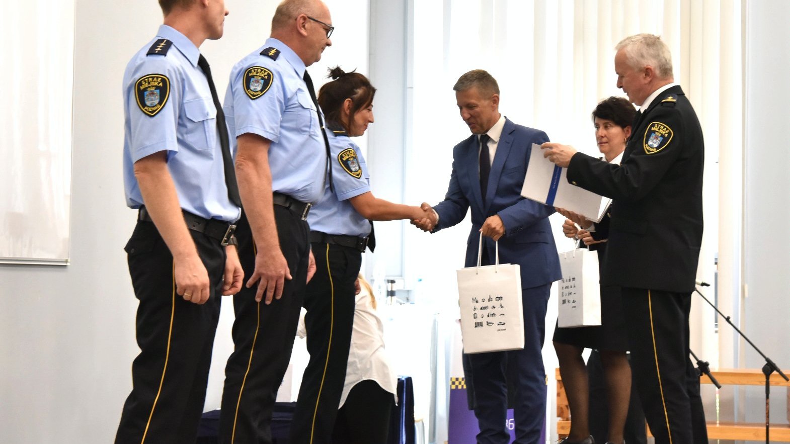 Zdjęcie przedstawia dyrektora i komendanta wręczających wyróżnienia strażnikom.