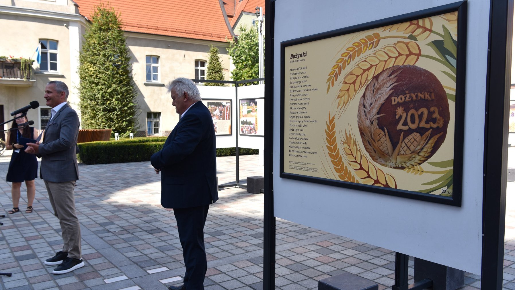 Zdjęcie przedstawia plakat z wierszem i grafiką chleba oraz uczestników konferencji.