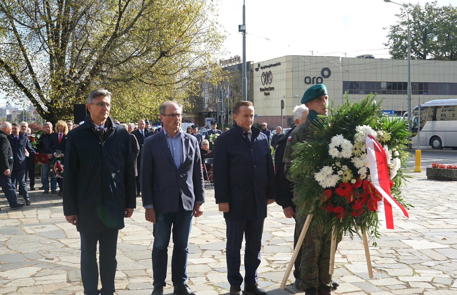 Na zdjęciu czterej mężczyźni składający wiązankę - grafika artykułu