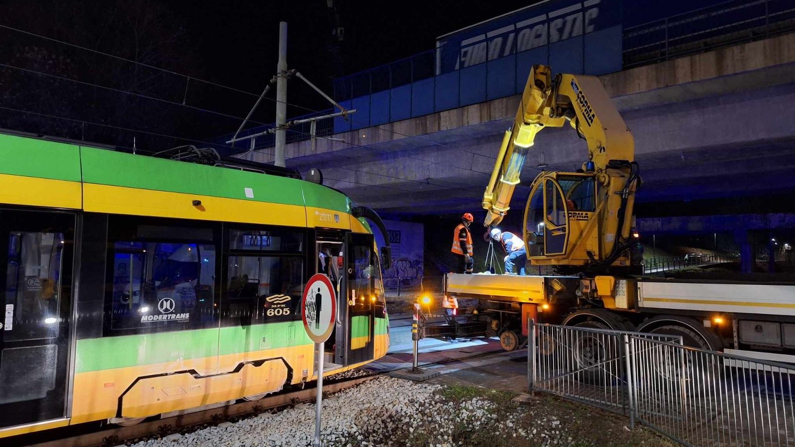 Zdjęcie przedstawia zepsuty tramwaj oraz maszynę i ludzi, którzy będą go holować lub naprawiać.