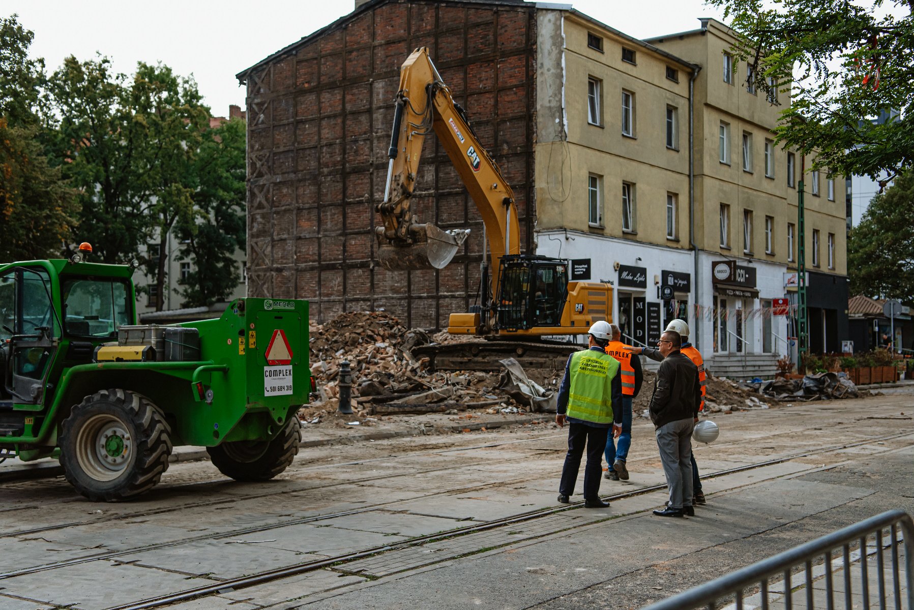 Na zdjęciu czterej mężczyźni przyglądający się rozbiórce kamienicy - grafika artykułu