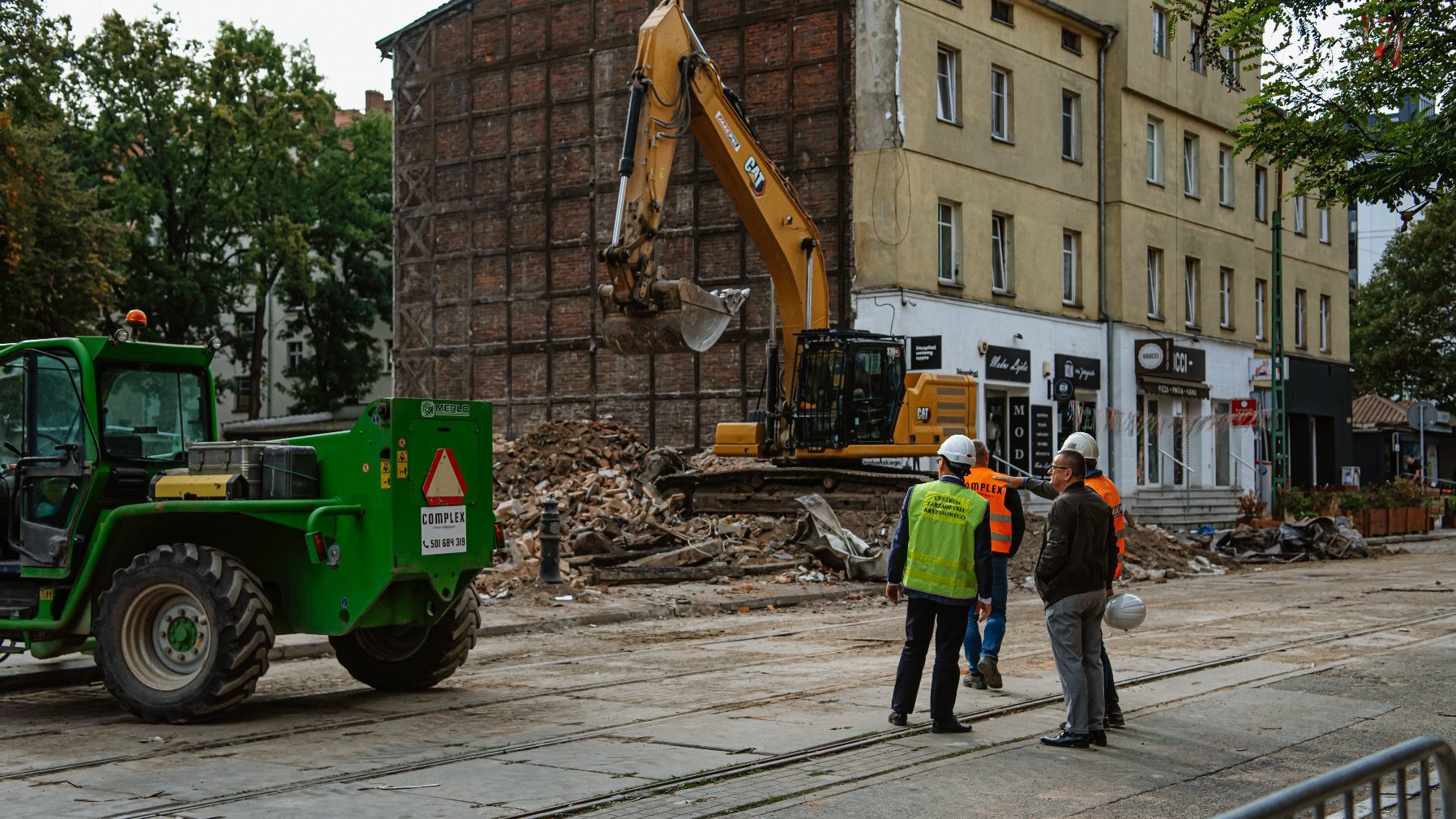 Na zdjęciu czterej mężczyźni przyglądający się rozbiórce kamienicy