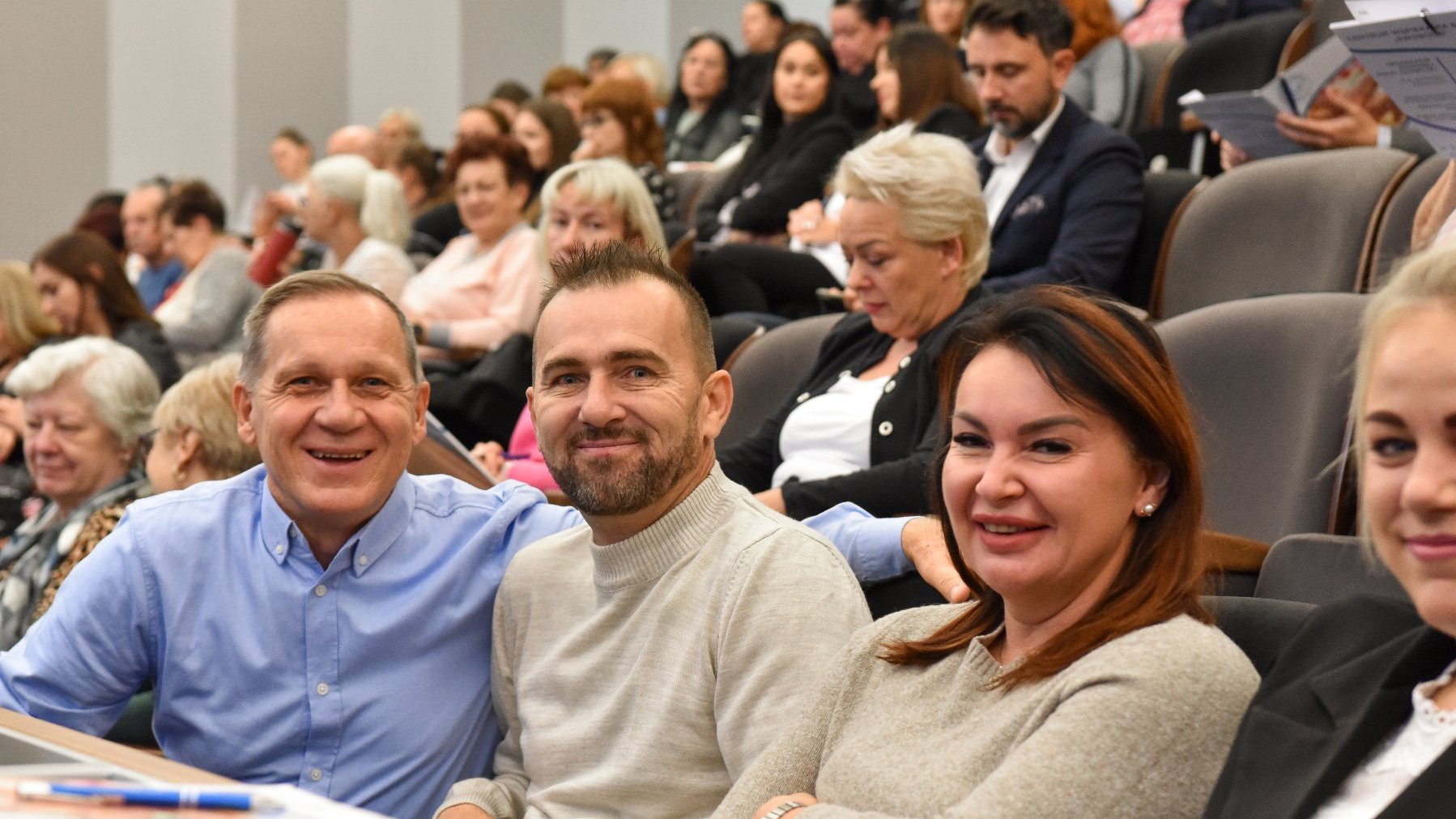 Na zdjęciu uśmiechnięci ludzie na sali konferencyjnej