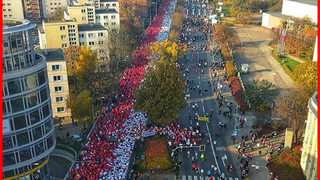 Plakat z informacjami o biegu ze zdjęcieme tłumu biegaczy ułożonych we flagą biało-czerwoną flagę w tle