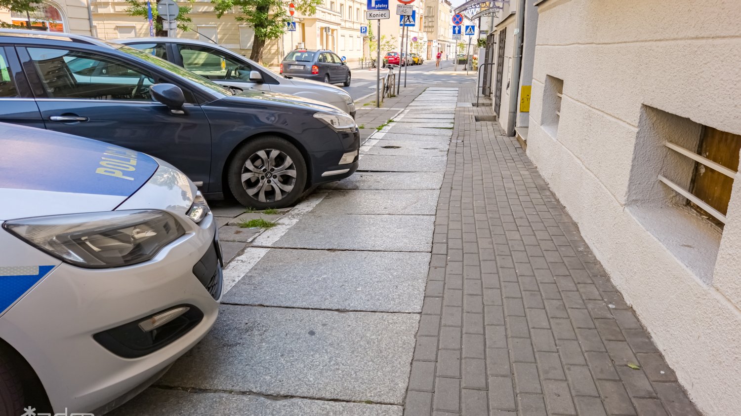 Zniszczony chodnik i parkujące na nim samochody