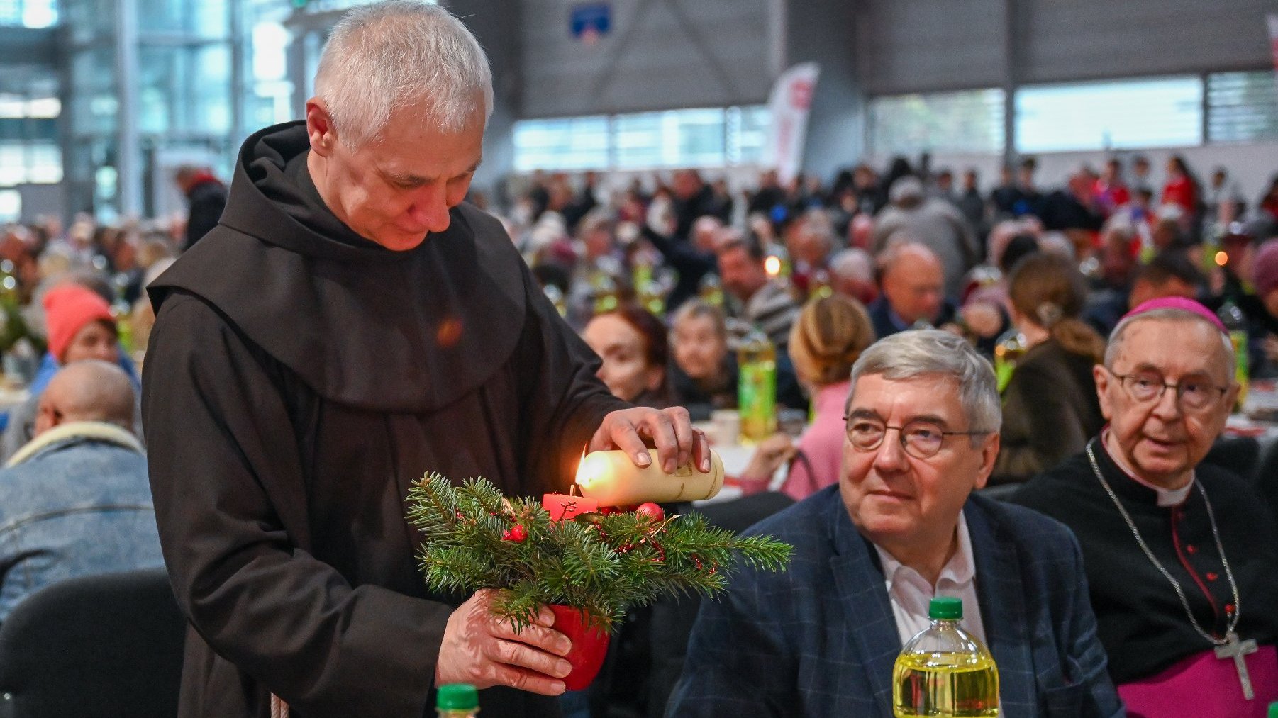 Na zdjeciu zakonnik zapalający świecę