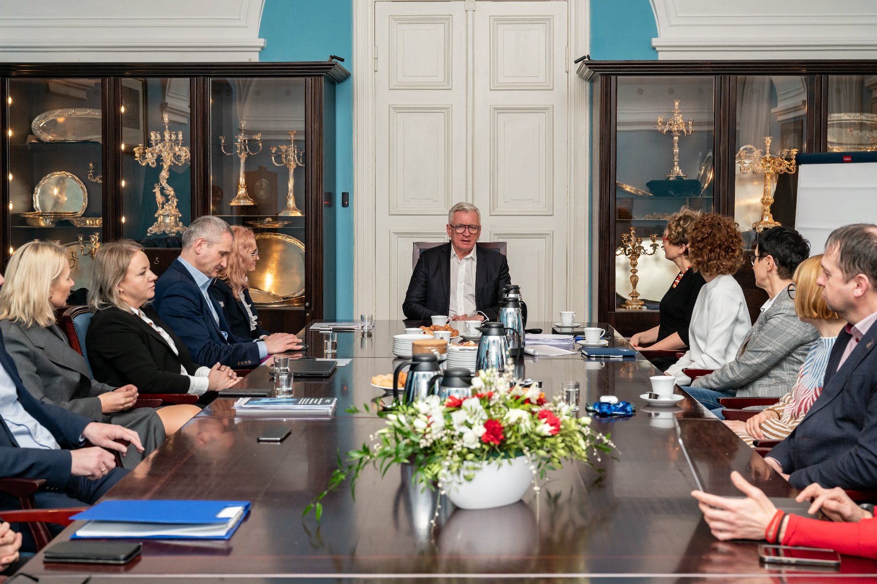 Na zdjeciu grupa ludzi za stołem, u szczytu stołu siedzi prezydent Poznania - grafika artykułu